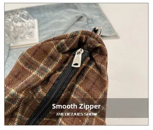 Close-up of smooth silver metal zipper on a brown plaid fabric tote bag detail