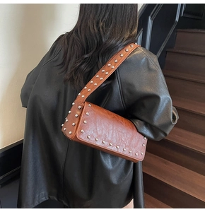 Close-up of brown textured leather shoulder bag featuring stylish silver stud detailing