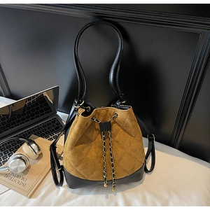Brown suede bucket bag with diamond quilting and gold chain strap in a lifestyle setting