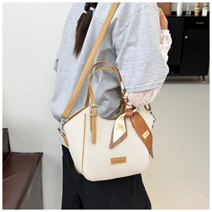 Detail of cream houndstooth handbag with brown leather trim and silk scarf handle decor