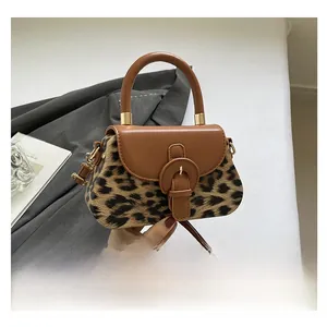Gros plan du sac bandoulière léopard avec poignée en cuir brun et détails dorés