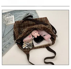 Capacity display of the brown plaid tote bag showing umbrella, wallet, and a magazine