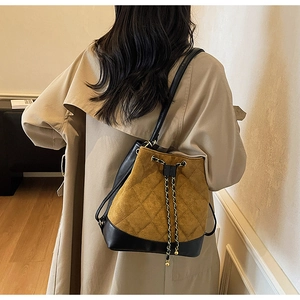 Detail view of the brown quilted suede bucket bag with leather trim on model