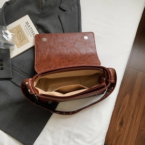 Macro shot of brown retro crossbody bag featuring interior pockets and silver rivet straps