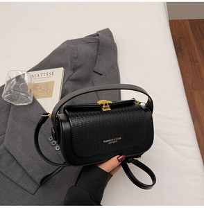 Detail of black leather box bag with woven texture flap and gold metal buckle