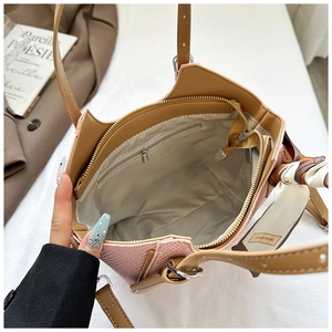 Detail view of pink woven bag with brown leather handles and inner zipper pocket