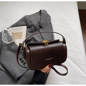 Close-up of vintage brown crossbody bag with woven texture lid and gold shell-shaped lock