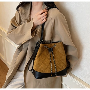Detail of brown quilted suede bucket bag with gold chain drawstring and leather trim