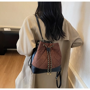 Close-up of quilted drawstring bucket bag with gold chain and mixed texture details