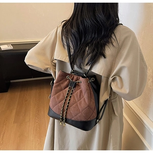 Detail of drawstring bucket bag with quilted patterns and gold metal chains on model