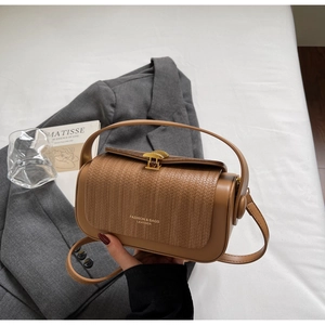 Detail of vintage brown leather crossbody bag with woven texture and gold fan-shaped lock