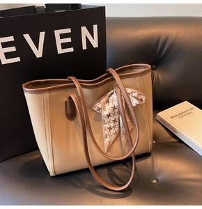 Detail of a beige tote bag with brown leather trim and houndstooth silk ribbon bow decor
