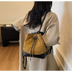 Detail of tan suede drawstring bucket bag with quilted patterns and chain straps