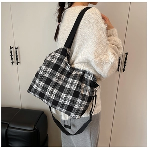 Classic black and white checkered tote bag shown worn as a stylish crossbody bag