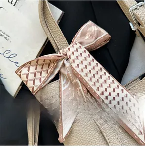 Detail display of geometric silk scarf tied on lychee pattern leather bag handle
