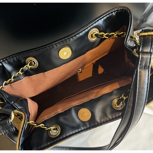 Detail of black leather bucket bag featuring gold magnetic clasp and spacious interior