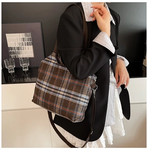 Macro detail of vintage plaid pattern fabric and metal buckle on brown crossbody bag