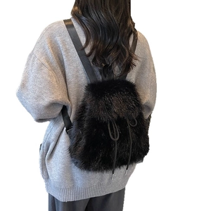 Plush black faux fur backpack for women featuring a minimalist drawstring flap design
