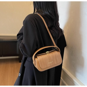 Detail of the brown leather box bag featuring woven texture flap and gold hardware lock