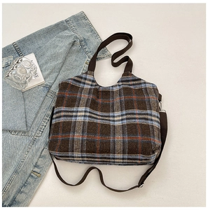 Close-up of retro plaid tote bag with brown woven handles and adjustable shoulder strap