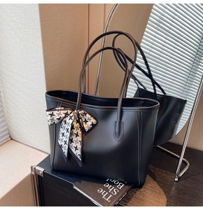 Detail of black leather tote bag featuring a chic houndstooth scarf on a wooden surface