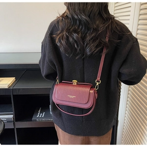 Detail of burgundy vintage box bag with gold clasp and textured flap for a retro style