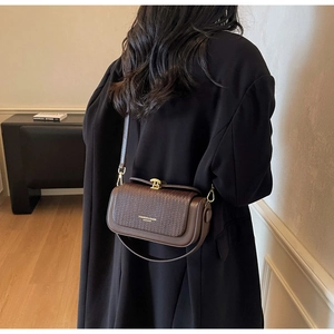 Detail of vintage brown leather box bag featuring a woven flap and gold twist lock