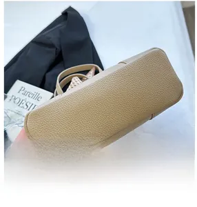 Detail view showing the reinforced bottom and lychee texture of the beige handbag