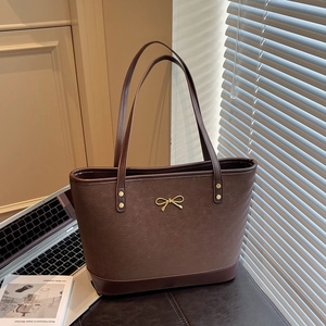 Classic dark brown leather tote bag with gold bow accent and large capacity for work