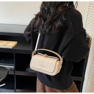 Detail of beige leather crossbody bag featuring woven texture and gold metal clasp
