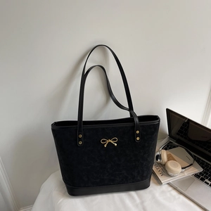 Large black tote bag with gold bow and rivets, shown with a laptop on a desk