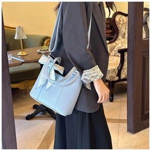 Detail of light blue lychee pattern leather handbag with printed silk scarf decoration