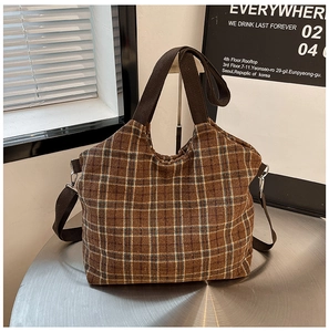Detailed macro view of the thick brown plaid fabric texture and sturdy tote bag handles