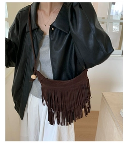Détail du sac croissant en daim marron foncé avec longues franges et perle en bois