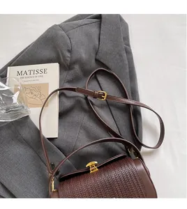 Detail of woven texture on a brown vintage box bag with gold buckle and adjustable strap