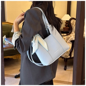 Detail of light blue lychee pattern leather shoulder bag with decorative printed silk scarf