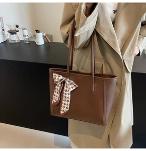 Brown tote bag with houndstooth ribbon detail worn with a trench coat in a café