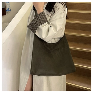 Close-up of large olive green suede hobo bag worn with a classic beige trench coat
