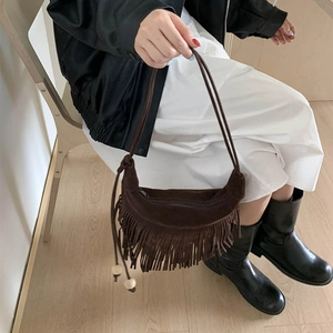 Détail d'un sac demi-lune en daim marron avec de longues franges et perles en bois