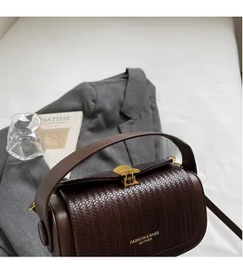 Detail of dark brown leather handbag featuring woven texture and gold shell-shaped lock