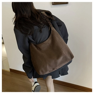 Detail view of large brown suede hobo shoulder bag styled with a professional dark blazer