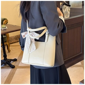 Detail of off-white lychee leather tote bag with elegant silk scarf on handle