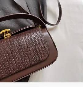 Detail of woven texture flap and golden lock on vintage brown leather crossbody bag