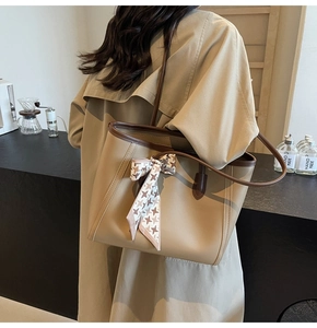 Brown tote bag with decorative scarf shown in a stylish cafe setting by a model