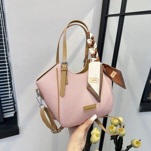 Pink woven handbag with synthetic leather handles and decorative scarf on the handle