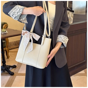 Detail of cream lychee texture tote bag featuring a decorative silk scarf and logo