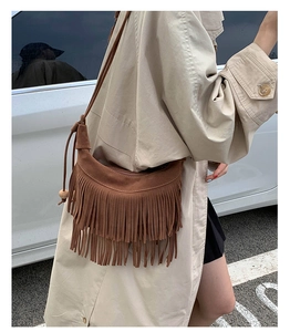 Gros plan du sac bandoulière marron à franges avec perle en bois et texture daim mat