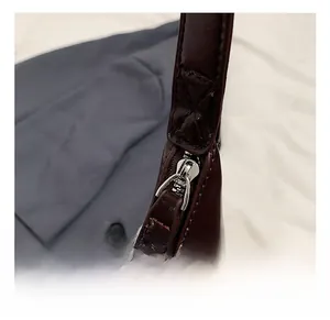 Gros plan sur la fermeture éclair argentée et les coutures de précision du sac en cuir brun