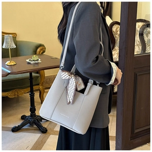 Detail of beige lychee leather handbag with decorative silk ribbon and shoulder strap