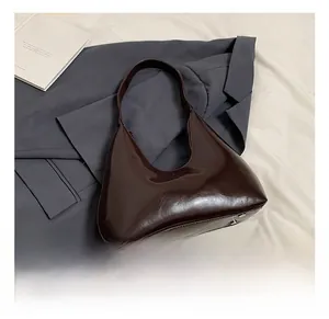 Détail du sac croissant vintage en cuir huilé poli montrant les pieds métalliques